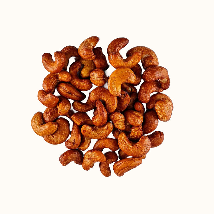 Close-up van geroosterde cashewnoten met tamari coating op witte achtergrond