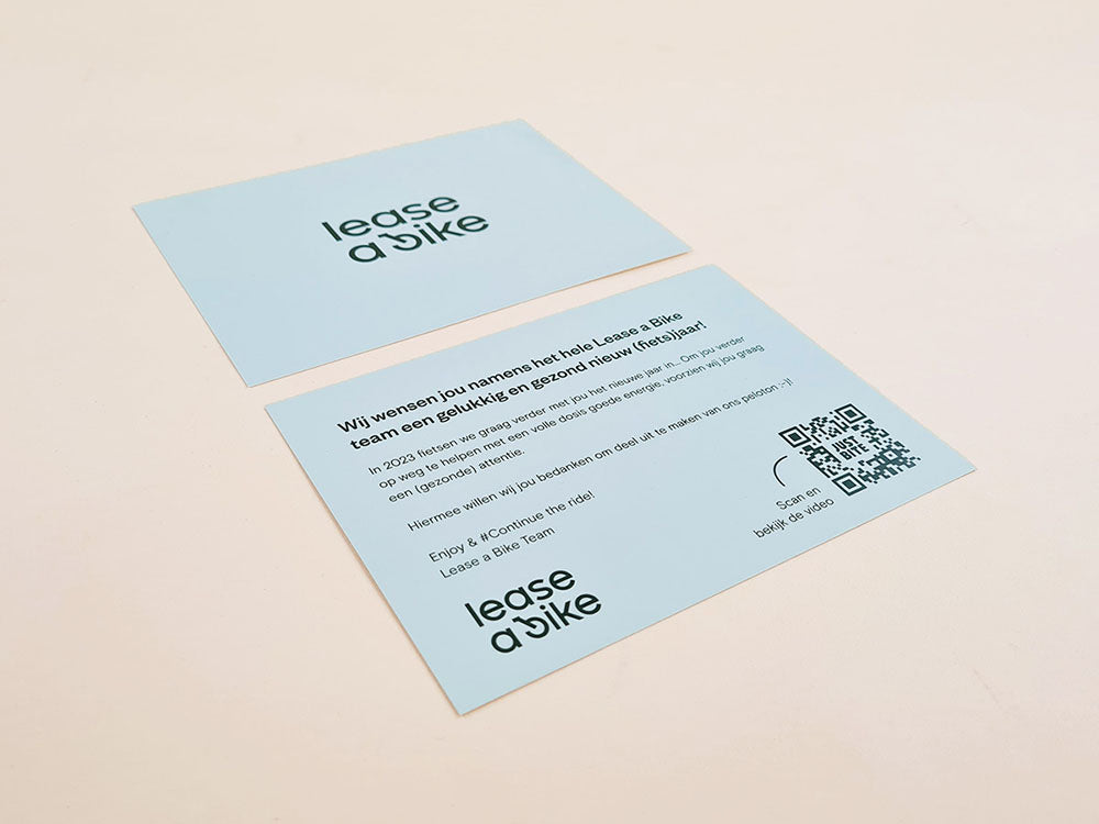 Voor- en achterkant van een gepersonaliseerd kaartje voor Lease a Bike met een nieuwjaarswens, het bedrijfslogo en een QR-code om een video te bekijken.