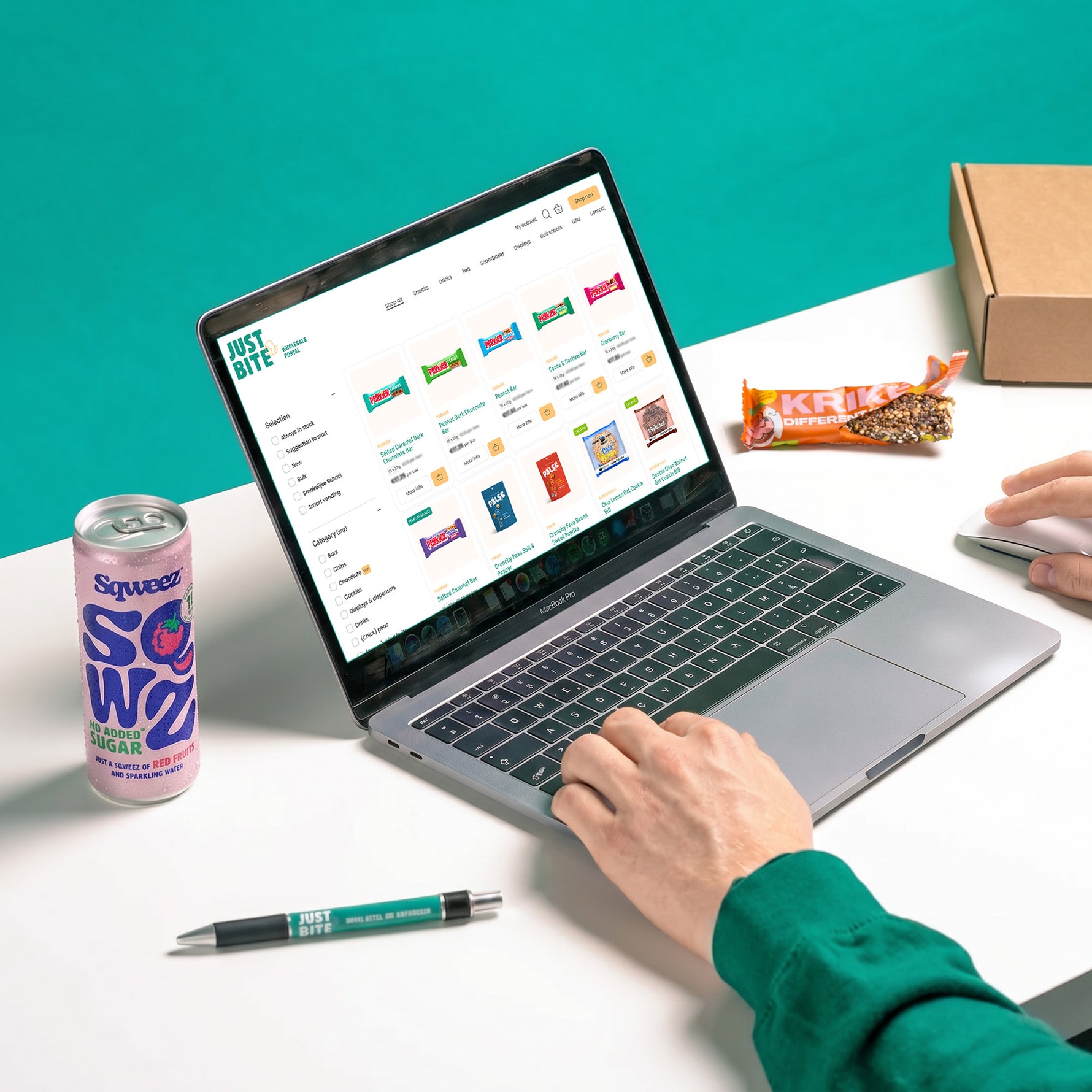 Persoon gebruikt JustBite wholesale portal op laptop met snacks en dranken