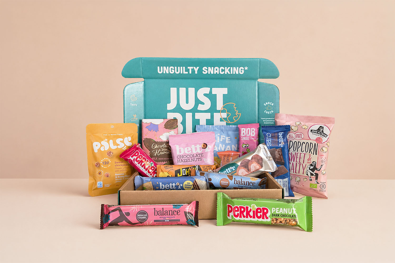 Een geopend JustBite zoet eindejaarsgeschenk gevuld met een divers assortiment aan zoete snacks, waaronder fairtrade chocoladerepen, biologische popcorn en fruitbites.