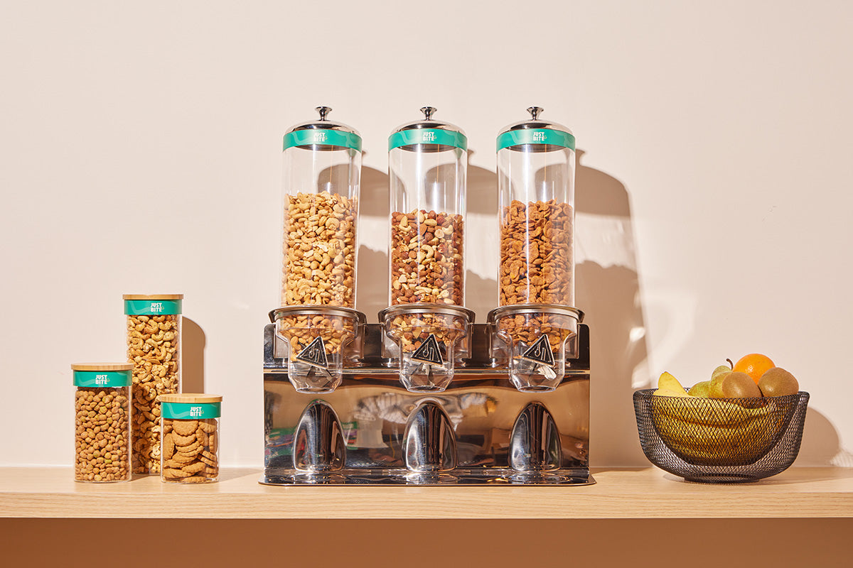Stijlvolle dispensers en glazen potten gevuld met verse noten en snacks in een kantoorkeuken. Met ons verpakkingsvrije bulk-aanbod geniet je team van verrassend lekkere snacks met veel minder afval.