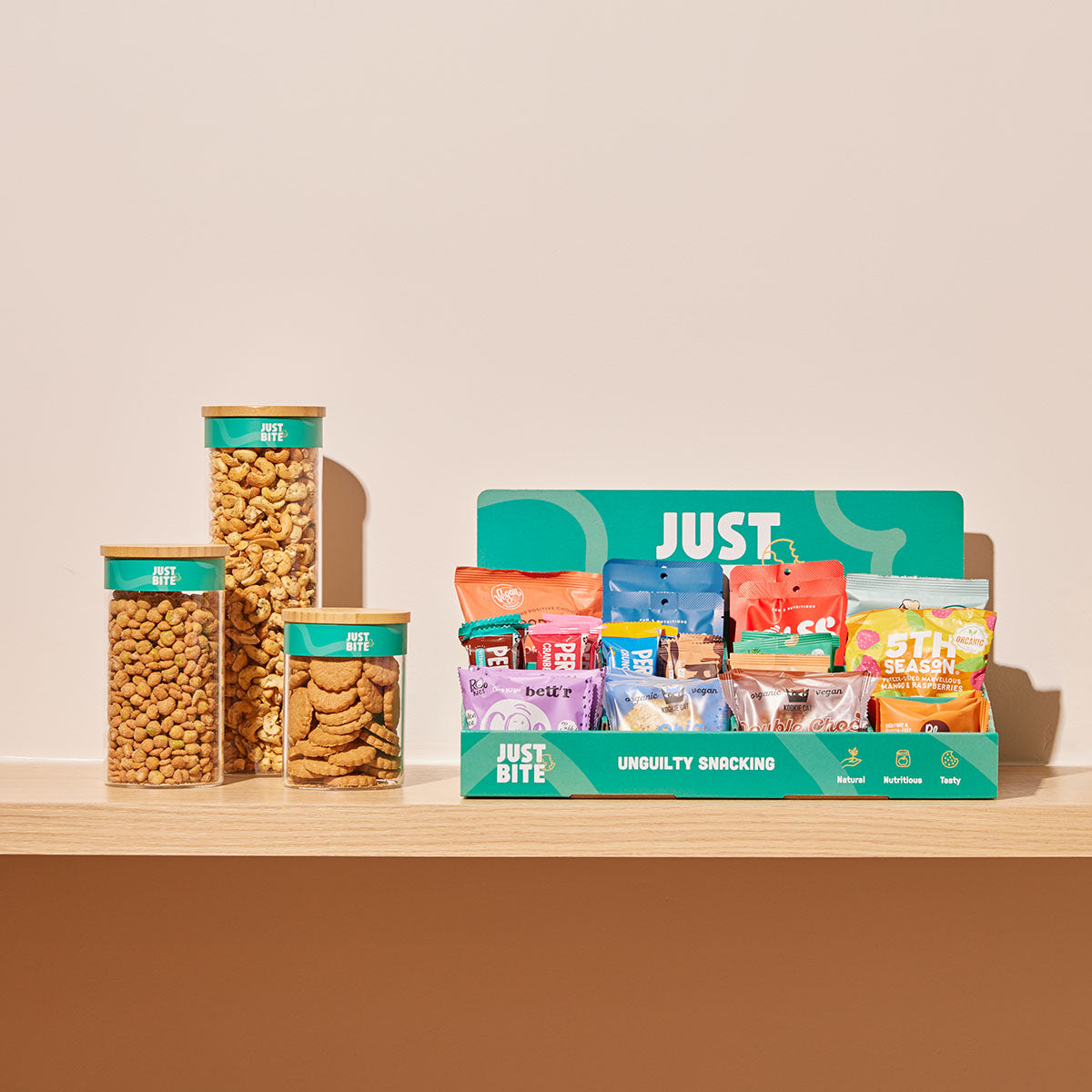 Glazen bewaarpotten met bulk snacks naast een JustBite display met individueel verpakte repen. Een voorbeeld van onze pragmatische aanpak: verpakkingsvrij waar het kan, slim verpakt waar het moet voor hygiëne en versheid.