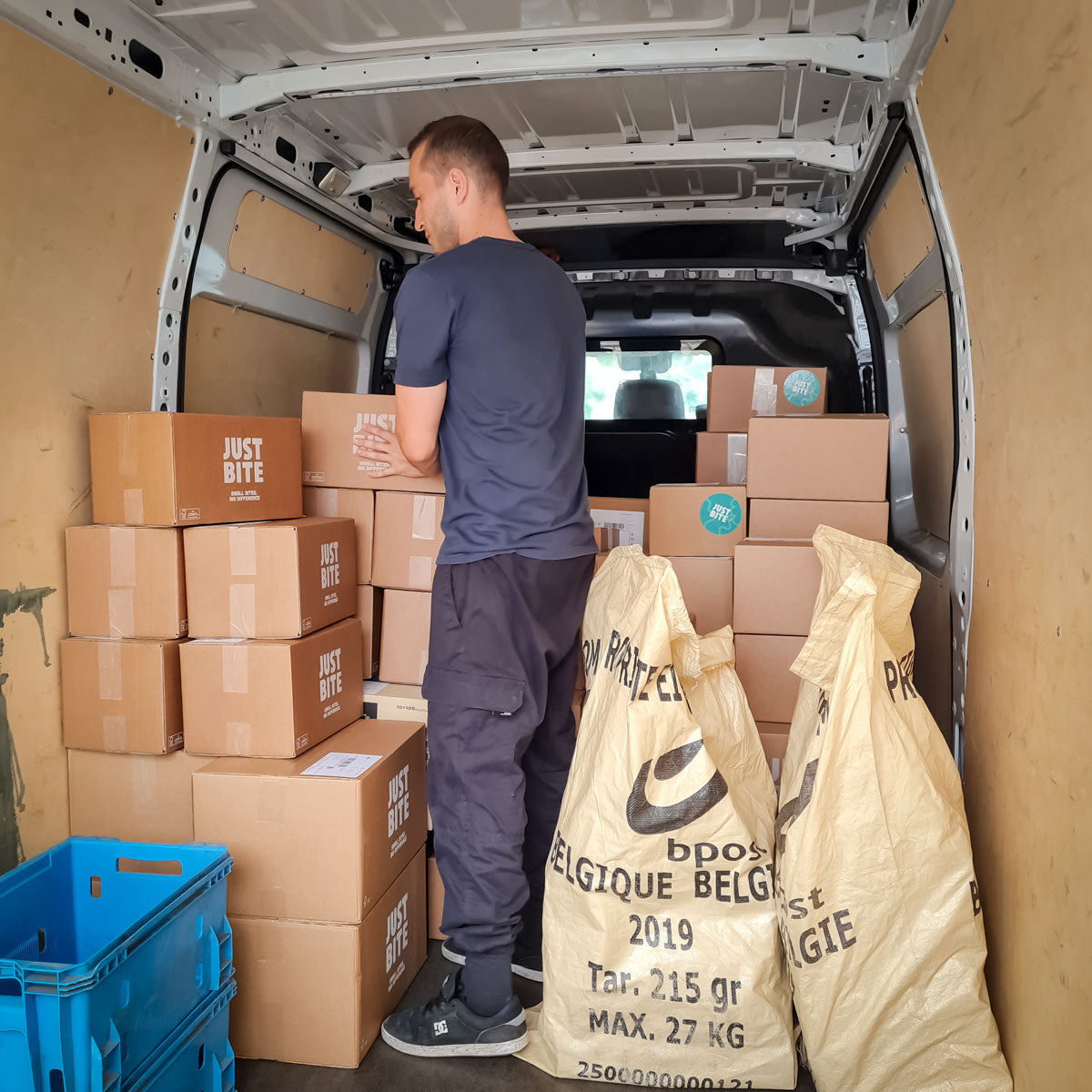 Chauffeur laadt JustBite dozen en bpost zakken in voor een gebundelde levering. Een voorbeeld van slimme logistiek waarbij we meeliften op bestaande routes om lege kilometers te vermijden.