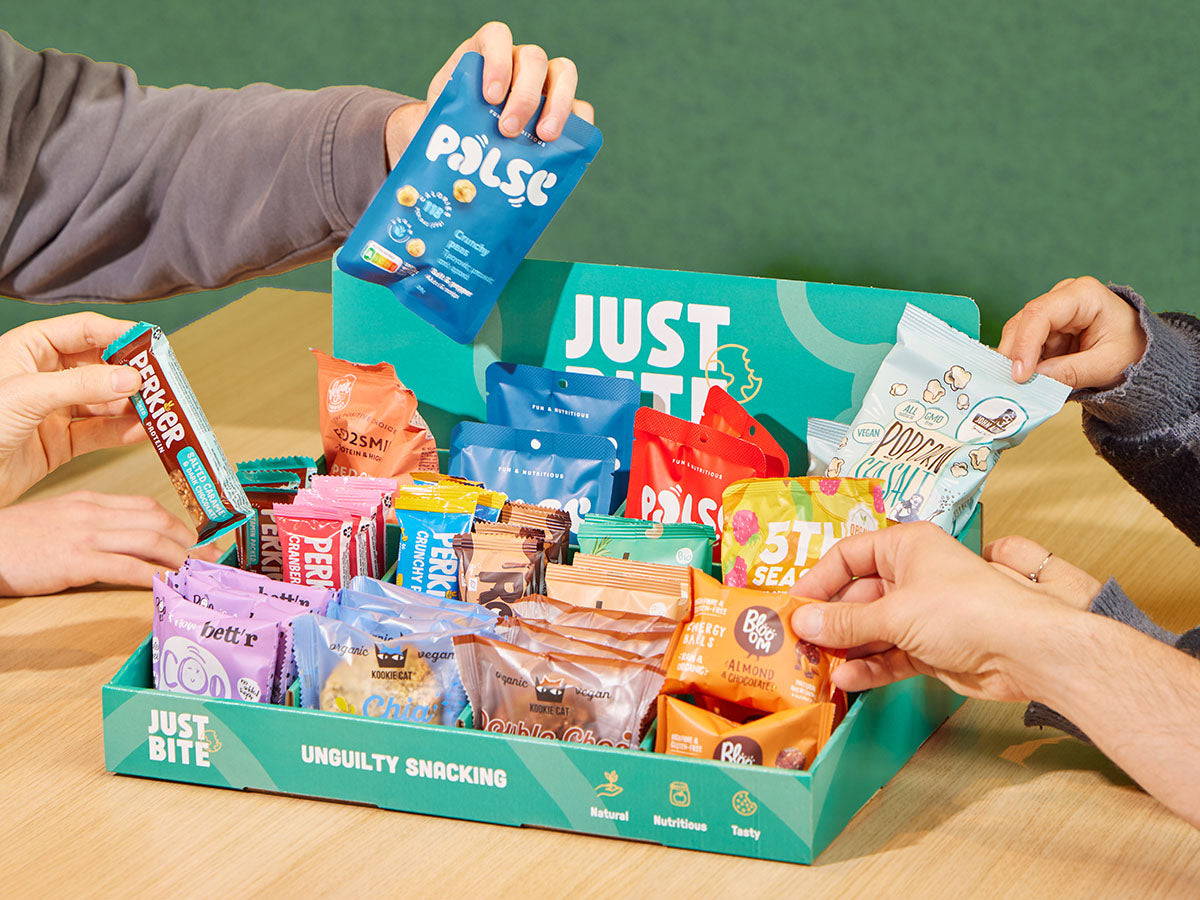 Collega's delen verrassend lekkere snacks uit een goedgevulde JustBite box op kantoor. 